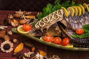 Sturgeon decorated with lemon and tomatoes on a green plate