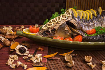 Sturgeon decorated with lemon and tomatoes on a green plate