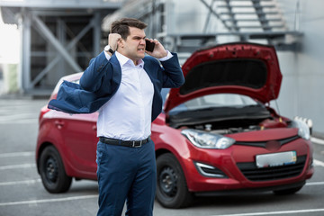Angry businessman shouting in phone because of broken new car