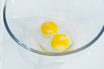 Two raw broken eggs in a bowl