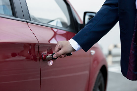 Closeup of businessman hand opening car door