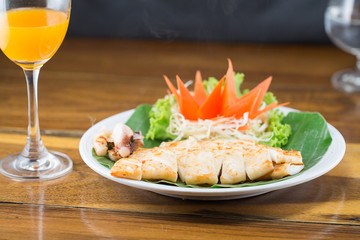 Thai style grill squid and orange juice on wood table