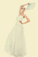 Full length bride in wedding gown holds fan