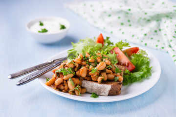 Stewed white beans in tomato sauce on toasted bread