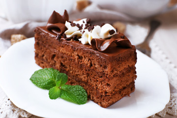 Tasty piece of chocolate cake on wooden table background