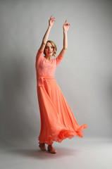 Naklejka premium Beautiful young woman in color dress posing on light background