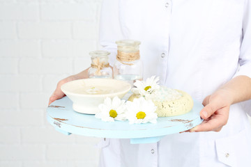 Beauty therapist holding tray of spa treatments, close-up