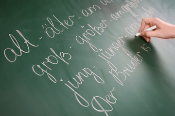 Teacher hand writing grammar sentences on blackboard background