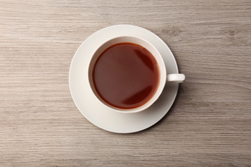 Cup of coffee on wooden table, top view