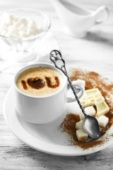 Cup of latte coffee art on wooden table, on light background