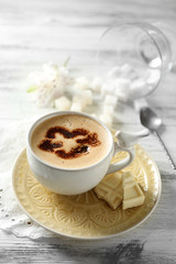 Cup of latte coffee art on wooden table, on light background