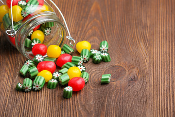 Colorful candies in jar on wooden background