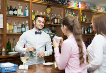 Two girls flirting with barman .