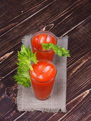 Bloody mary cocktails served with celery on wooden background