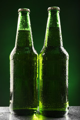 Glass bottles of beer on dark green background