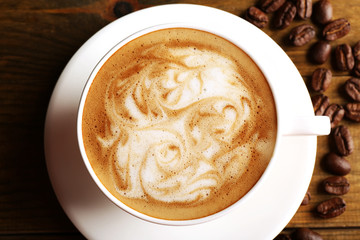 Cup of coffee latte art with grains on wooden table, top view