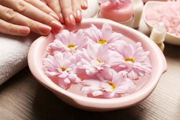 Naklejka na ściany i meble Female hands and bowl of spa water with flowers, closeup