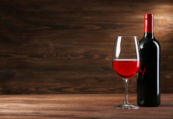 Wineglass and bottle on wooden background