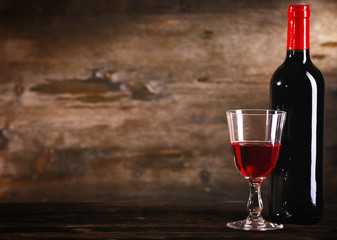 Wineglass and bottle on wooden background