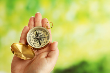 Female hand with compass on bright blurred background