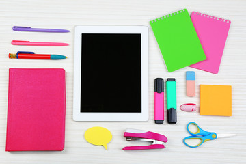 Digital tablet with stationery on wooden background
