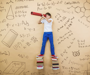 Cute little boy learning playfully in frot of a big blackboard