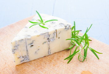 blue cheese with a sprig of rosemary on the kitchen board