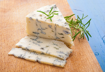 blue cheese with a sprig of rosemary on the kitchen board