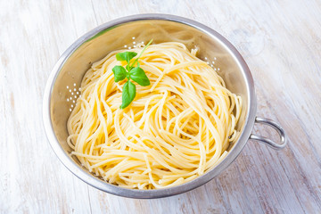 cooked pasta in the strainer on white wooden table