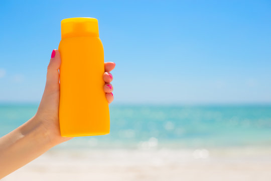 Woman Holding Sunscreen Bottle In Hand On The Beach