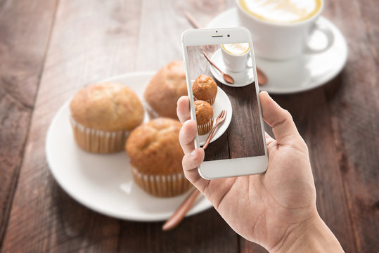 Taking photo of muffin and coffee on wooden table