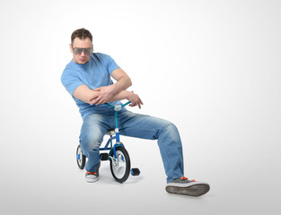 Cool man in a glamor glasses on children's bicycle