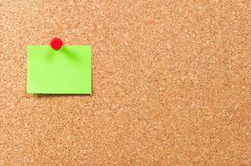 Single sticky note green on cork board horizontal