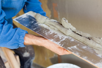 Man hand with trowel plastering a wall