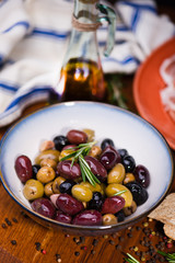 Olives in bow with prosciutto on wooden table