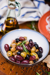 Olives in bow with prosciutto on wooden table