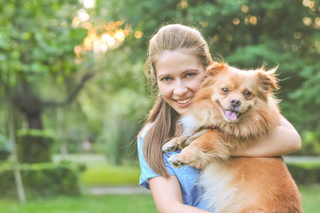 Girl holding dog in the park and smiling. Adopting a pet concept