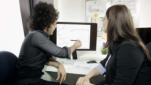 Modern cool architect showing project on computer to client medium shot