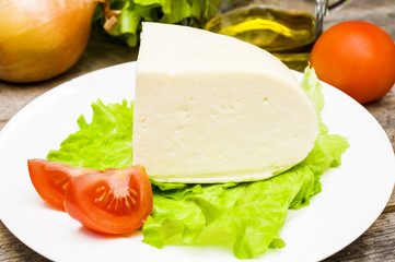 soft goat cheese in a bowl on a wooden table with vegetables