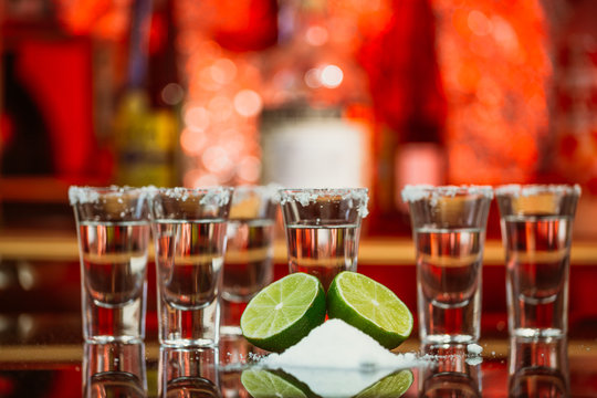 shots of tequila with lime and salt on a wooden table bar