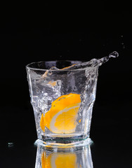 Slice of lemon splashing into a glass of water with