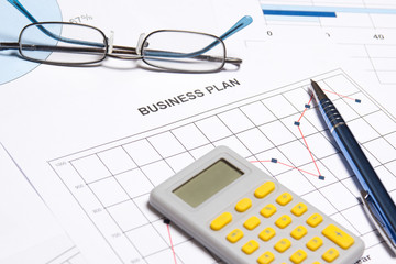 business plan concept - graphs, charts, pen and calculator