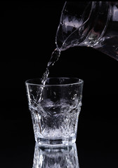 pouring water on a glass on black background