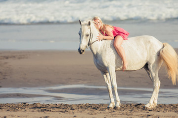 Fototapeta na wymiar Young happy woman lies and hugs the horse