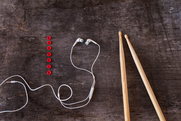 Fototapeta na wymiar Drumsticks and earphones laid on a wooden desk background
