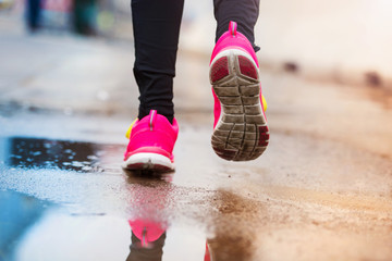 Unrecognizable young woman running in rainy weather