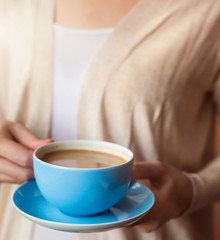 Unrecognizable woman holding a cup of coffee in her hands