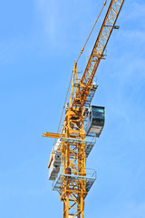 Yellow construction tower crane against blue sky