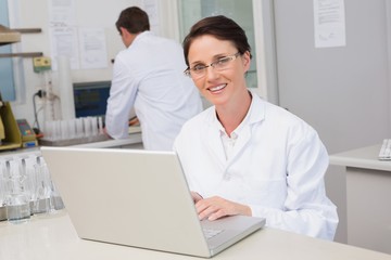 Fototapeta na wymiar Smiling scientist using laptop