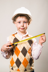 The boy in the construction helmet and a tape measure in hand